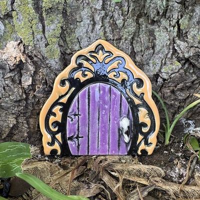 Fairy door in the colors black, and orange with a purple door