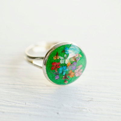 Real pressed flower and green glitter resin ring in reds, oranges, blues, purples, and pinks mix