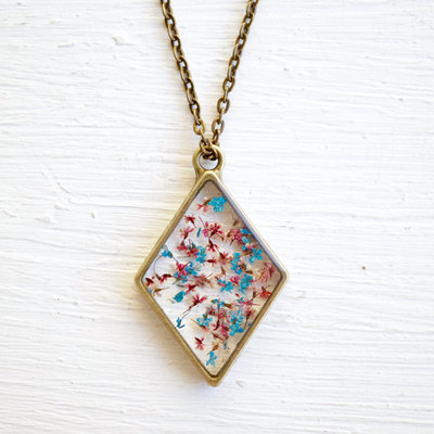 Real pressed flower and resin moon necklace in blues, pinks, and whites.